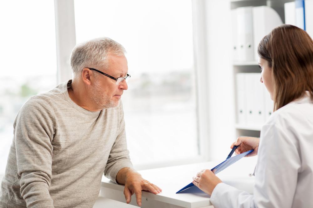 Imagen de un médico señalando algo a un hombre adulto mayor.