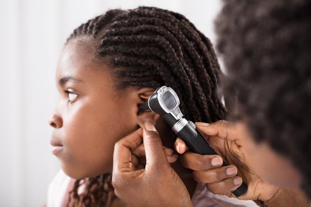 Foto de un proveedor de atención médica que revisa los oídos de una niña.