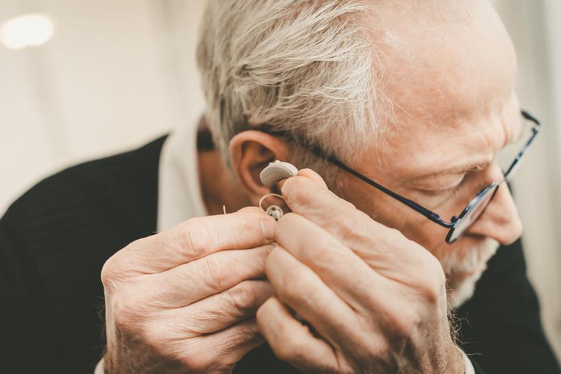 Imagen de un hombre mayor colocándose un audífono en el oído