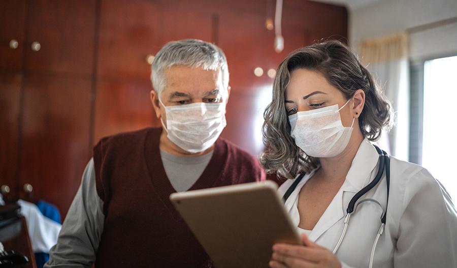 Un médico con cubreboca y su paciente con cubreboca miran juntos un gráfico.