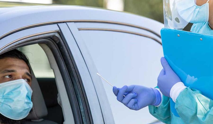 Un trabajador de la salud con cubreboca ayuda a un paciente durante una prueba de COVID-19.