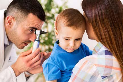 Médico examinando el oído de un niño.