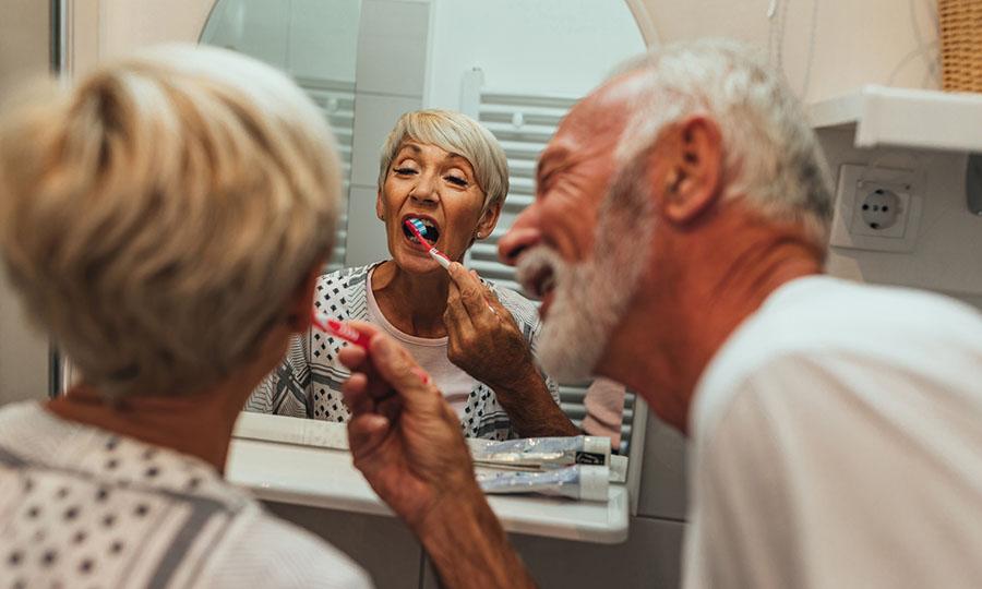 Anciano cepillando los dientes de su esposa