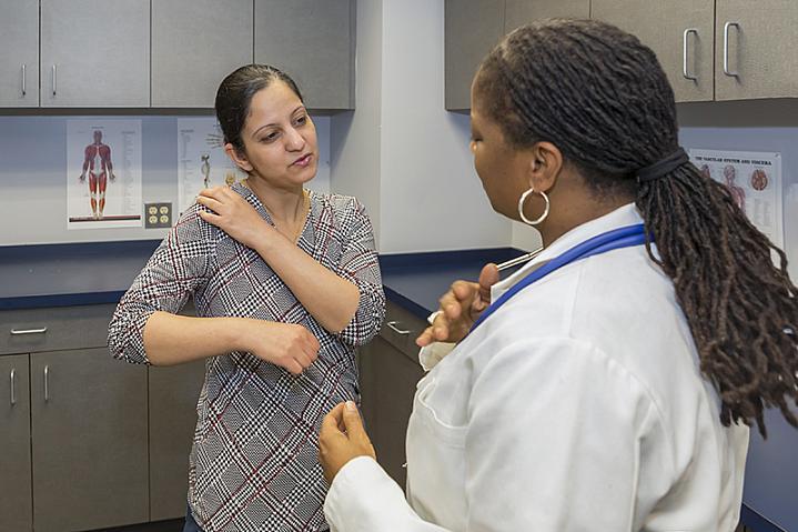 Una mujer que habla con su médica sobre el dolor del hombro.