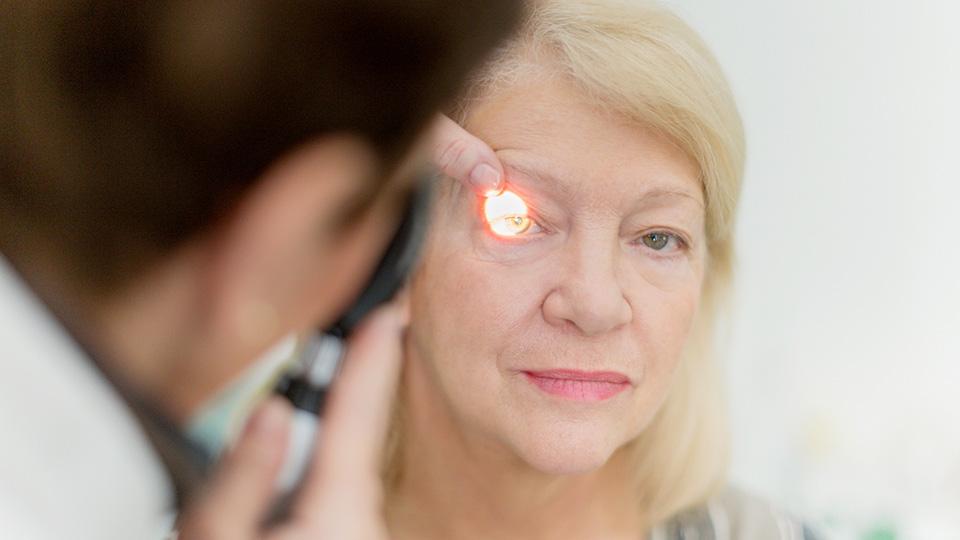 Foto de un oftalmólogo que le realiza un examen ocular a una mujer mayor