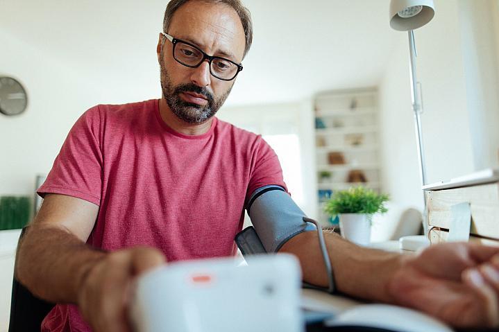 Foto de un hombre que controla su presión arterial en casa