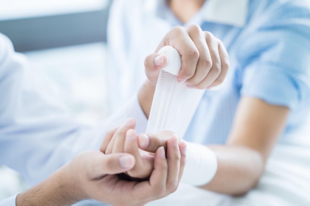 Foto ampliada de un médico vendando la extremidad superior de un paciente