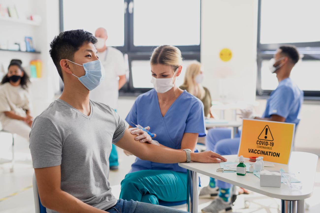 Foto de un hombre con mascarilla recibiendo la vacuna en una clínica