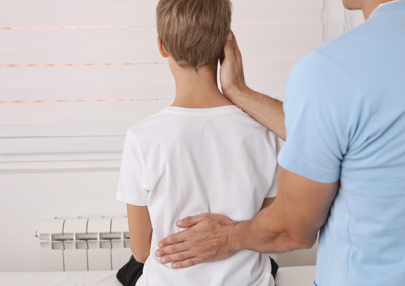 Imagen de un niño al que un profesional de la salud le examina la espalda
