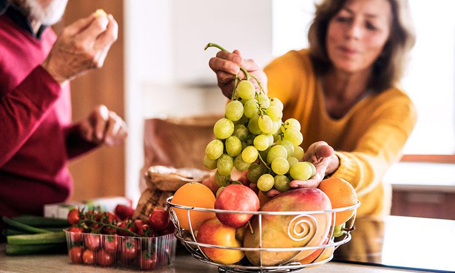 Mujer eligiendo uvas de la cesta de frutas