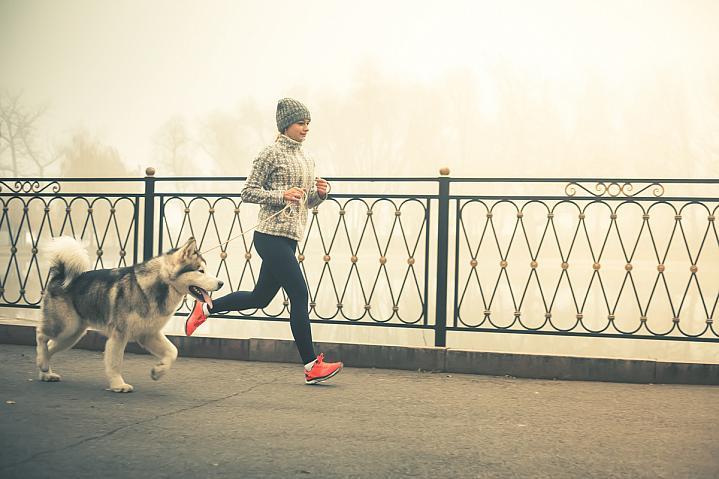 Una mujer trotando con un perro.