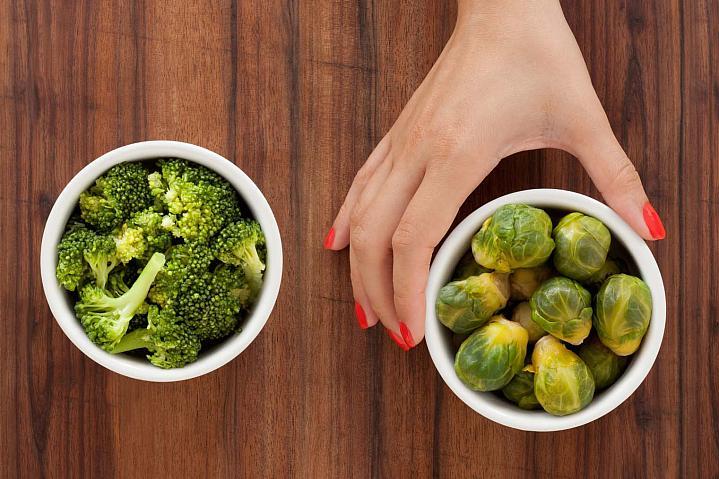 La mano de una persona que elige las coles de Bruselas en lugar de broccoli