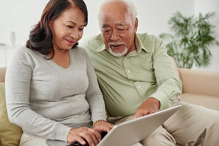 Foto de pareja de adultos mayores mirando información de salud en una computadora portátil.