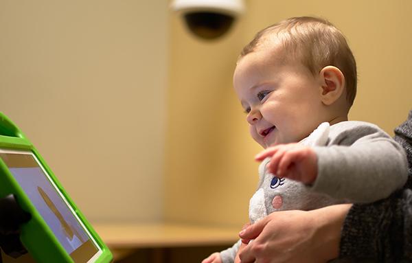 Imagen de un niño sonriente que mira a una persona en la pantalla de una tableta