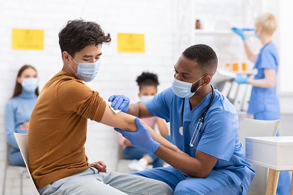 Imagen de un joven recibiendo una vacuna en un hospital