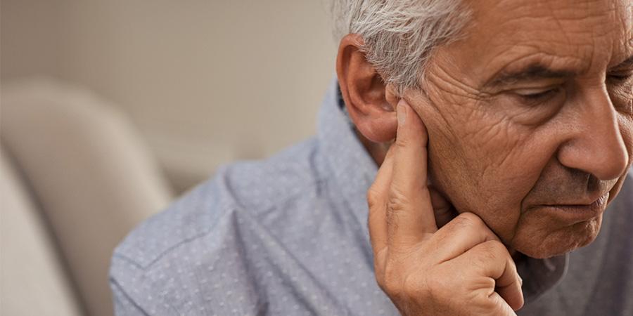 Imagen de un hombre sosteniendo los dedos en la oreja.