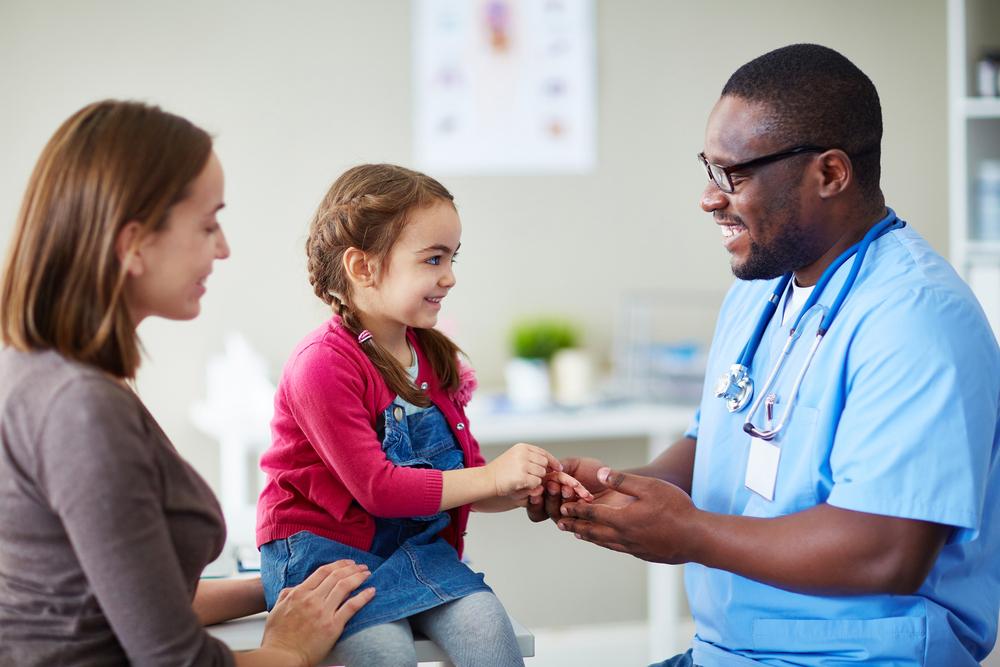 Foto de una niña y su madre hablando con un médico en una clínica