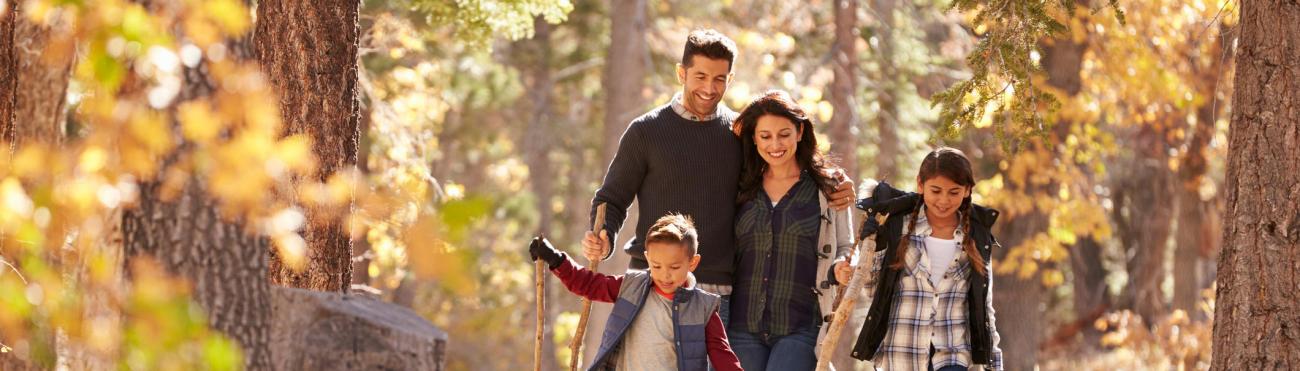 Familia feliz con dos niños caminando en un bosque