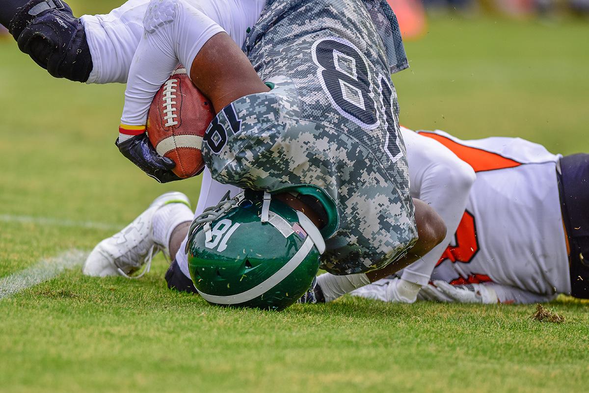 Imagen de un jugador de fútbol americano de secundaria cayendo de cabeza.