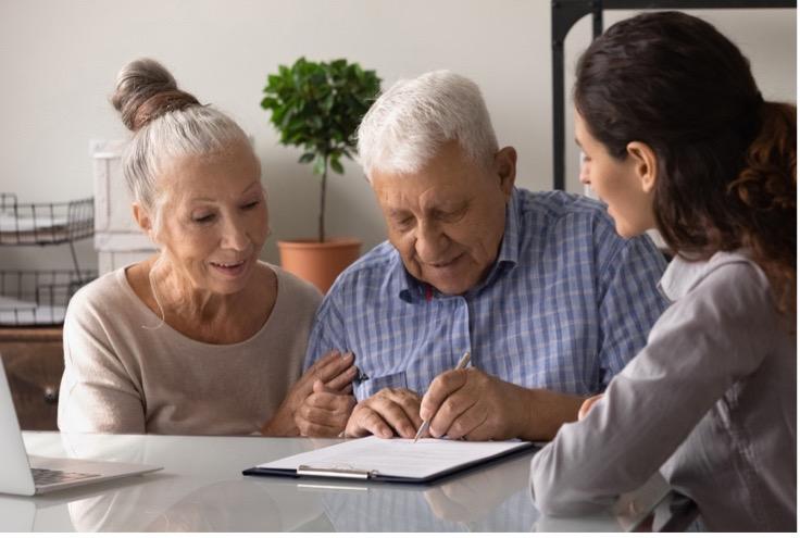 Imagen de un adulto mayor firmando papeles con su familia.