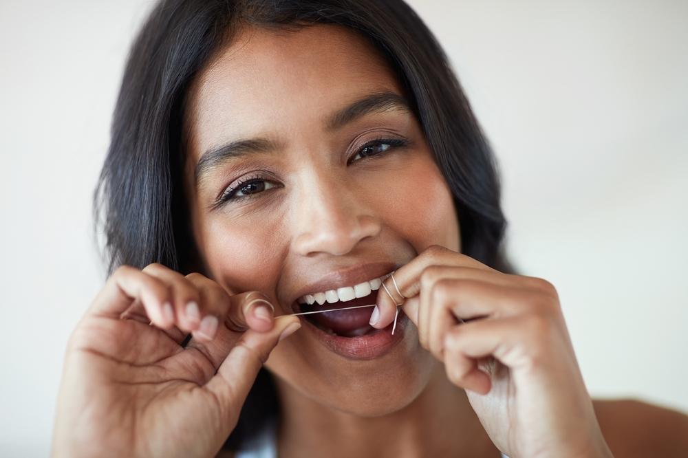 Imagen de una mujer utilizando hilo dental.