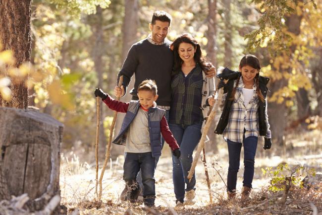 Familia feliz con dos niños caminando en un bosque