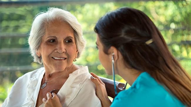 Foto de una médica que ausculta el corazón de un paciente mayor