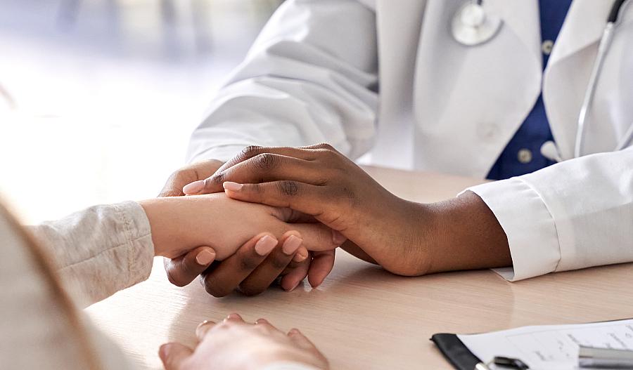 Una doctora sosteniendo la mano de una paciente para dar apoyo