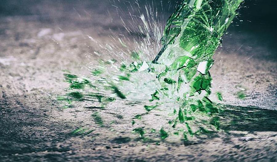 Imagen de una botella de vino verde golpeando el piso y rompiéndose