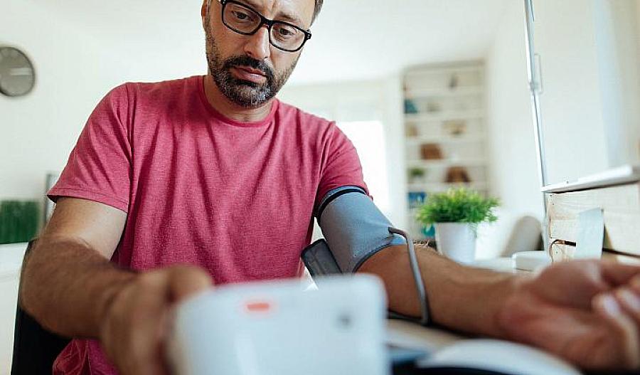 Foto de un hombre que controla su presión arterial en casa