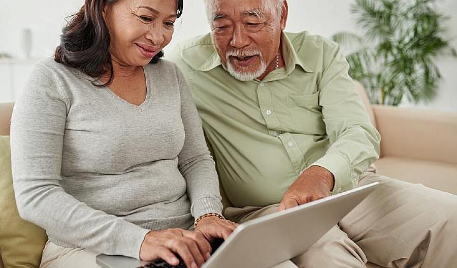 Foto de pareja de adultos mayores mirando información de salud en una computadora portátil.