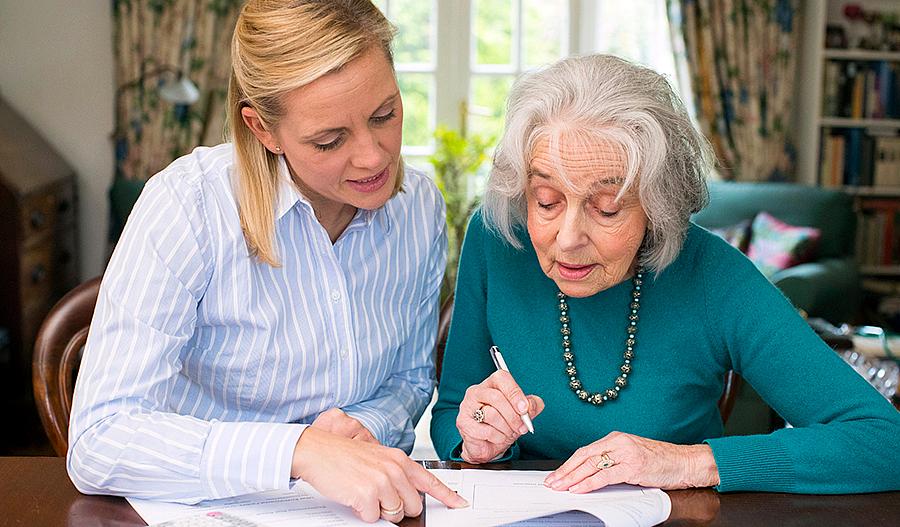 Foto de una mujer ayudando a una mujer mayor con el papeleo