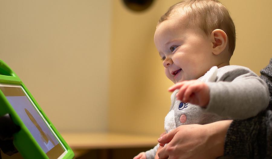 Imagen de un niño sonriente que mira a una persona en la pantalla de una tableta