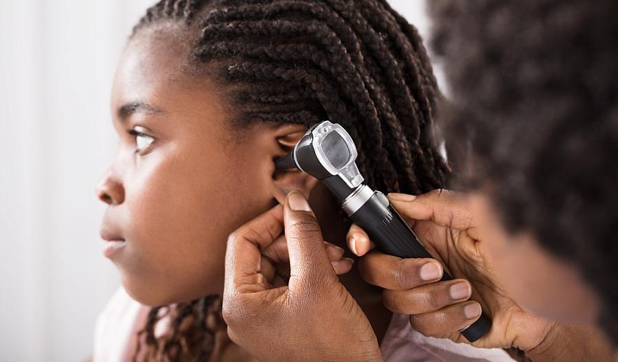 Foto de un proveedor de atención médica que revisa los oídos de una niña.