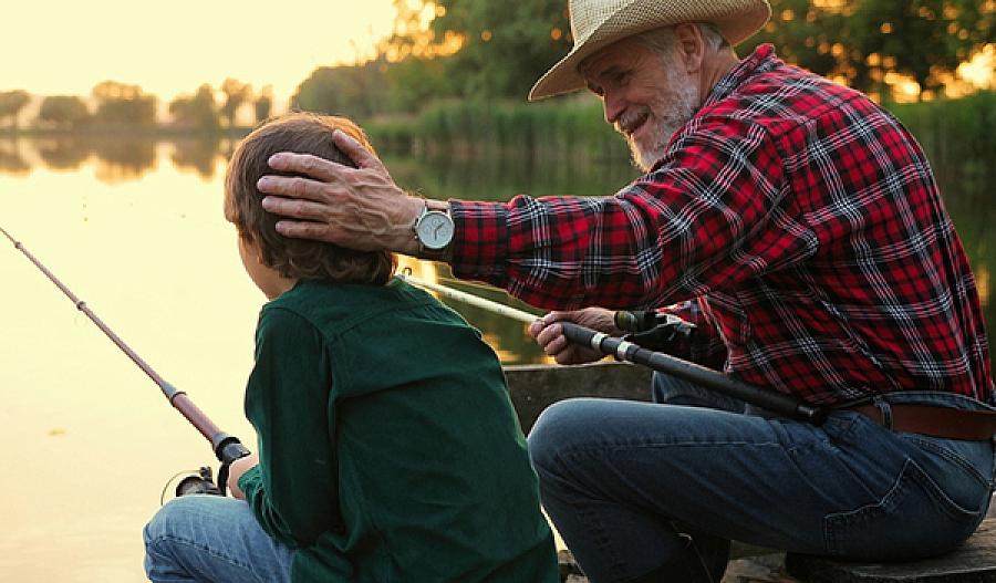 Imagen de un hombre conversando con su nieto mientras pesca.