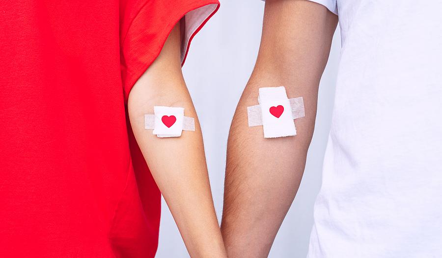 Imagen de donantes de sangre mostrando sus vendajes con corazones, después de la donación de sangre.