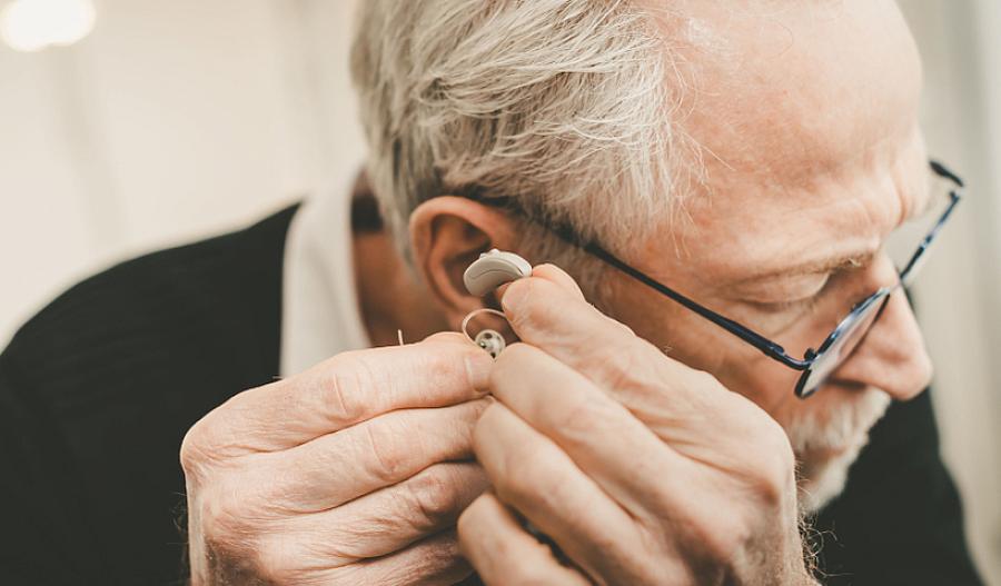 Imagen de un hombre mayor colocándose un audífono en el oído