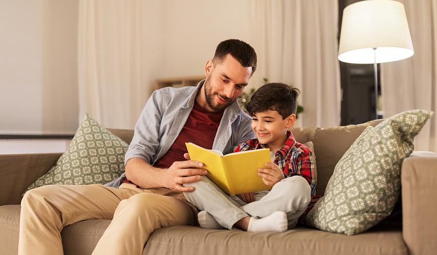 Fotografía de un padre y su hijo leyendo en un sofa