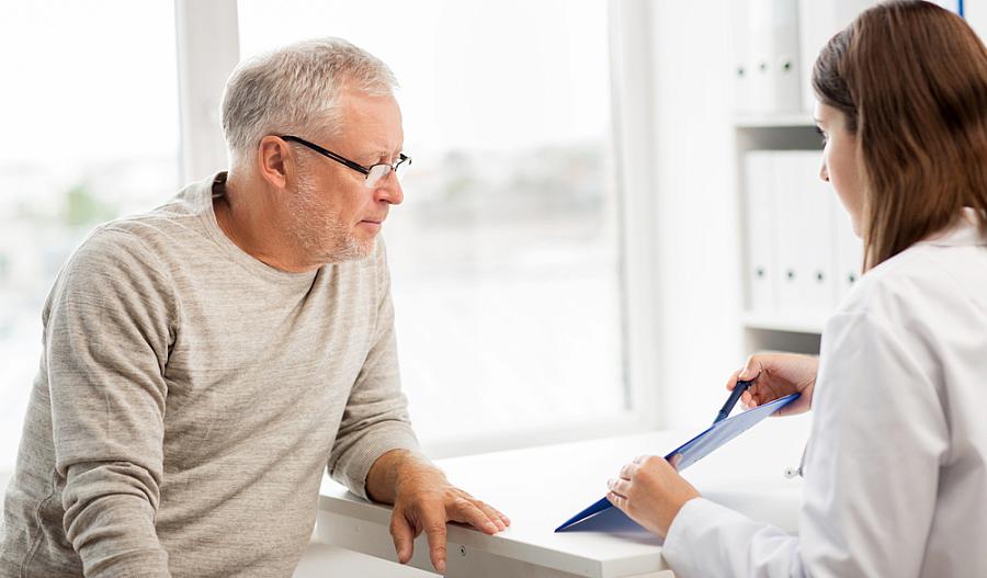 Imagen de un médico señalando algo a un hombre adulto mayor.