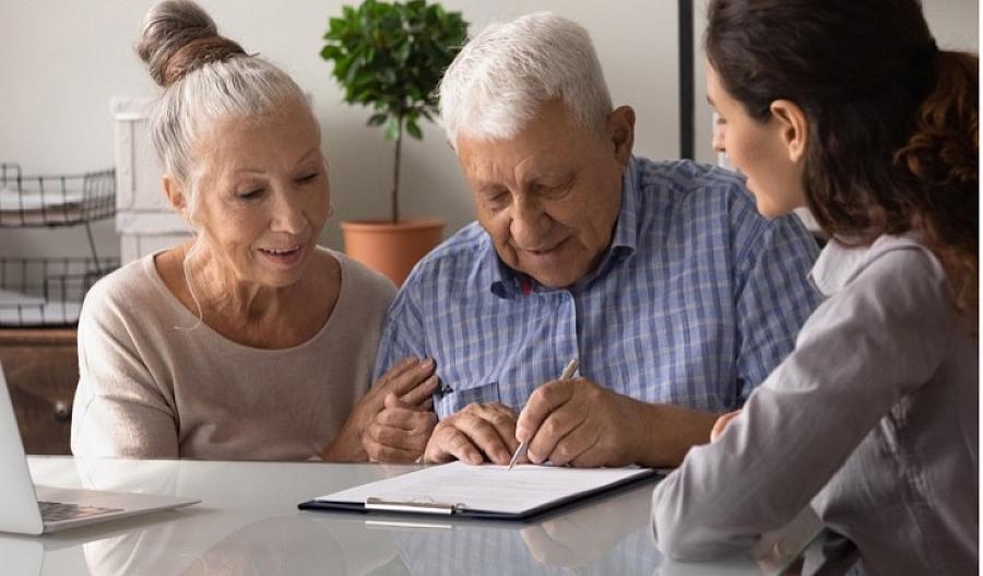 Imagen de un adulto mayor firmando papeles con su familia.