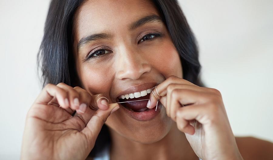 Imagen de una mujer utilizando hilo dental.