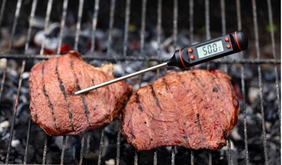 Imagen de filetes en una parrilla con un termómetro en uno de ellos.