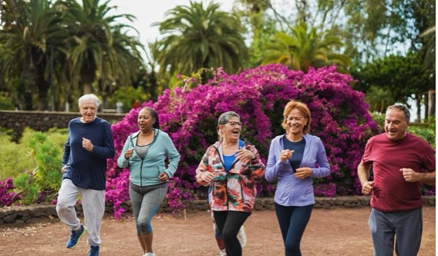 Una fotografía muestra a un grupo de adultos mayores sonriendo mientras corren al aire libre.  