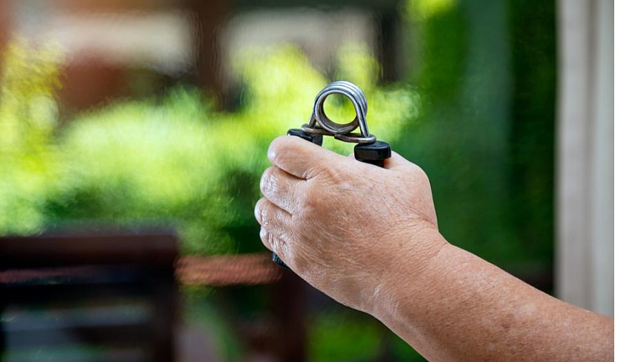 Una fotografía muestra la mano de un hombre usando unos ejercitadores de manos para fortalecerlas.