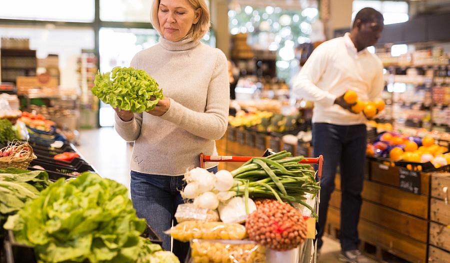 Fotografía de una mujer de mediana edad comprando verduras frescas.