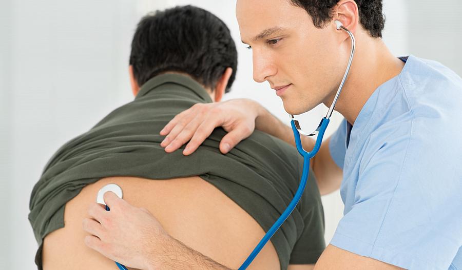 Una fotografía muestra a un doctor escuchando los pulmones de una persona, usando un estetoscopio.